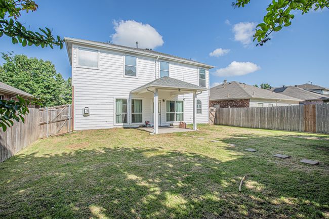 Rear view of house with a lawn, a fenced backyard, a gate, and a patio | Image 24