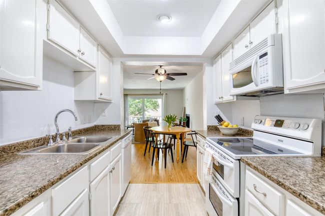 Kitchen with white appliances, a ceiling fan, and white cabinets | Image 17