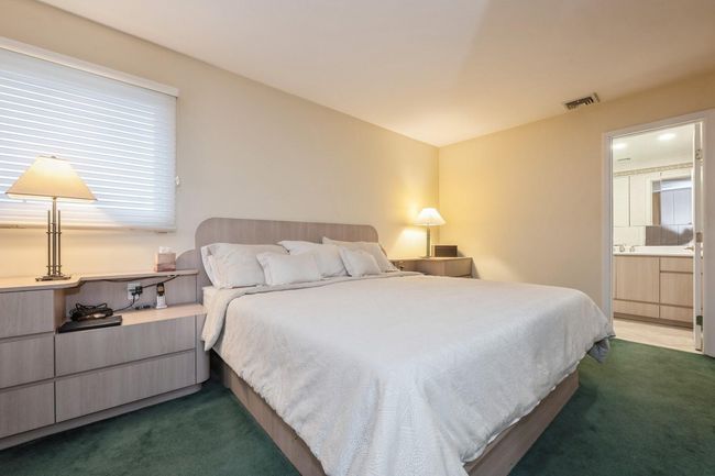 Bedroom with ensuite bathroom, carpet floors, and visible vents | Image 13