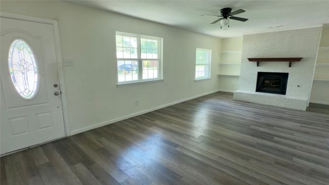 Unfurnished living room featuring dark wood-type flooring, a fireplace, a ceiling fan, and built in features | Image 27