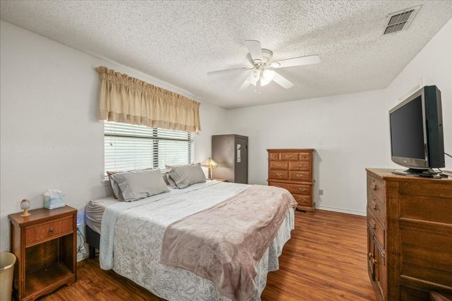 Bedroom featuring wood finished floors, a textured ceiling, and a ceiling fan | Image 19