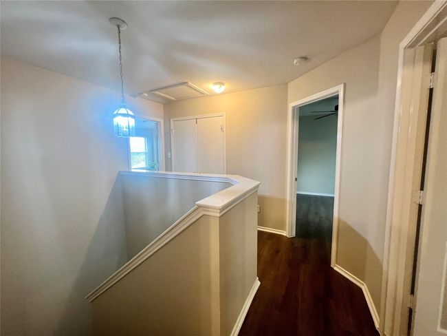 Hall with an upstairs landing, dark wood-type flooring, baseboards, and attic access | Image 13