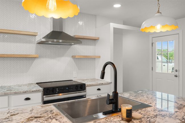Kitchen with range with electric stovetop, open shelves, wall chimney range hood, backsplash, and a sink | Image 9