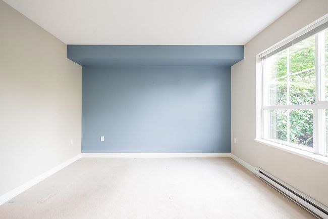 Empty room featuring baseboard heating, a wealth of natural light, light colored carpet, and baseboards | Image 12
