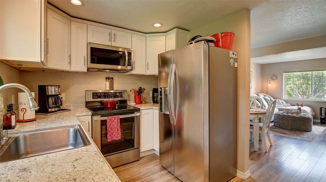 Kitchen featuring appliances with stainless steel finishes, light wood-style floors, white cabinets, light countertops, and recessed lighting | Image 12