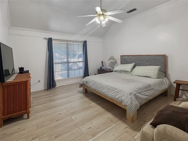 Bedroom featuring lofted ceiling, light wood-style flooring, ornamental molding, and a ceiling fan | Image 6