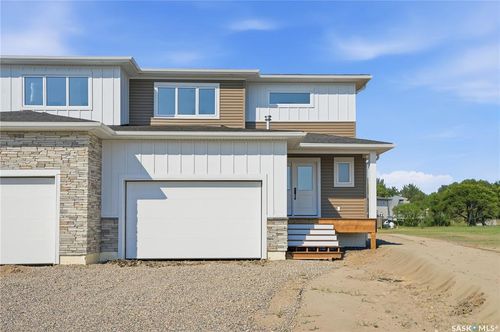 Contemporary exterior with stacked stone accents, vertical and horizontal siding, multiple windows, and an attached two-car garage | Card Image