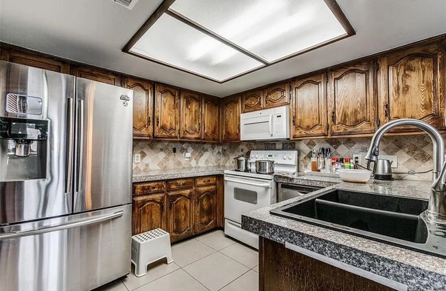 Kitchen with white appliances, a sink, light tile patterned floors, and backsplash | Image 6