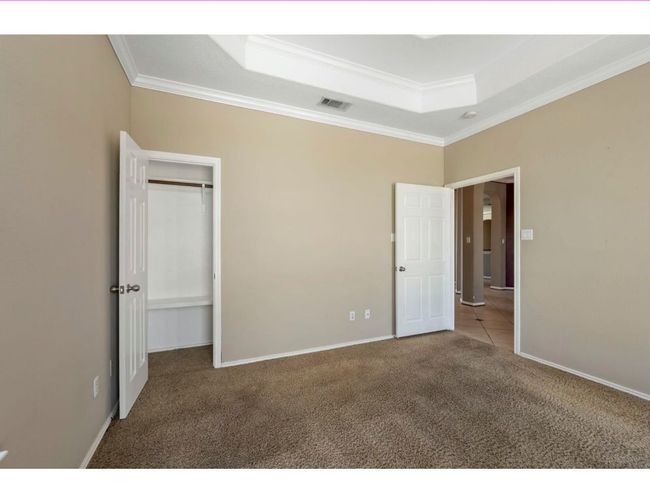 Unfurnished bedroom featuring ornamental molding, carpet flooring, a raised ceiling, and a closet | Image 8