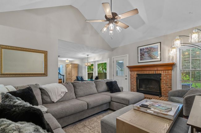 Living room with a fireplace, a ceiling fan, and high vaulted ceiling | Image 5