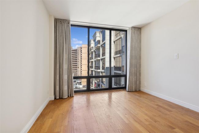 Spare room featuring a wall of windows, a view of city, light wood-style flooring, and baseboards | Image 7