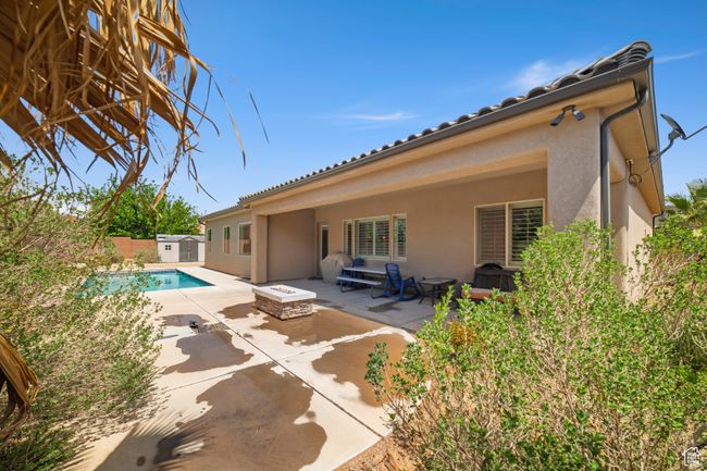 Back of property with a patio area, a storage shed, an outbuilding, a fenced in pool, and stucco siding | Image 34