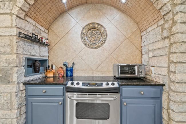Kitchen with dark countertops, blue cabinetry, stainless steel electric range oven, and a toaster | Image 12