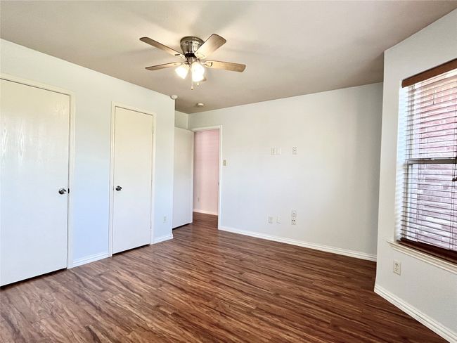 Unfurnished bedroom featuring wood finished floors, two closets, and ceiling fan | Image 26