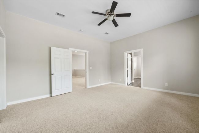 Unfurnished bedroom featuring light carpet, a spacious closet, baseboards, and a ceiling fan | Image 26