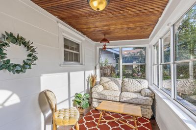 Curl up with a book on the East facing three season porch equipped with hardwood floors and a classic wood paneled ceiling | Image 2