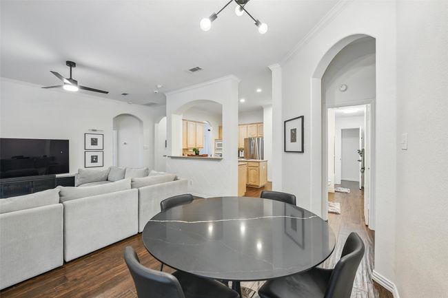 Dining room with crown molding, wood finished floors, ceiling fan, and arched walkways | Image 13