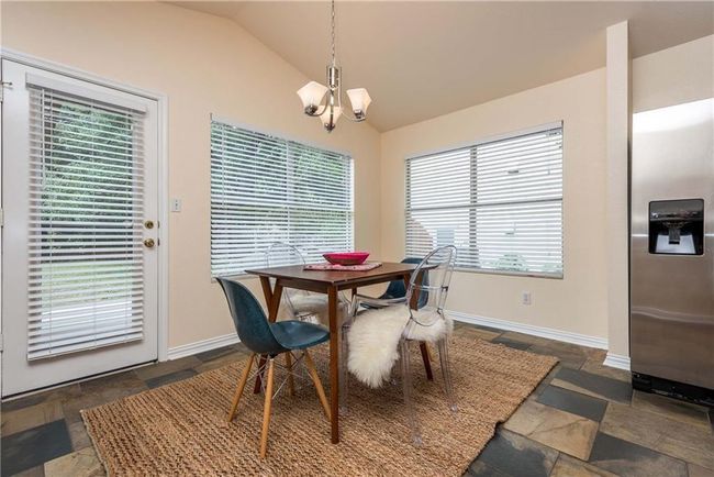 Dining space with stone tile flooring, vaulted ceiling, and a chandelier | Image 12