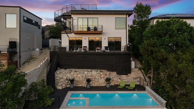 Rear view of house featuring stairway, a balcony, stucco siding, and a pool with connected hot tub | Image 33