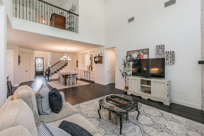 Living area with a chandelier, dark wood-style flooring, stairway, and a high ceiling | Image 12