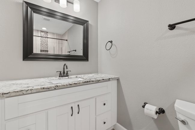 Secondary full bathroom has single sink vanity with granite counter tops and plenty of storage. | Image 23