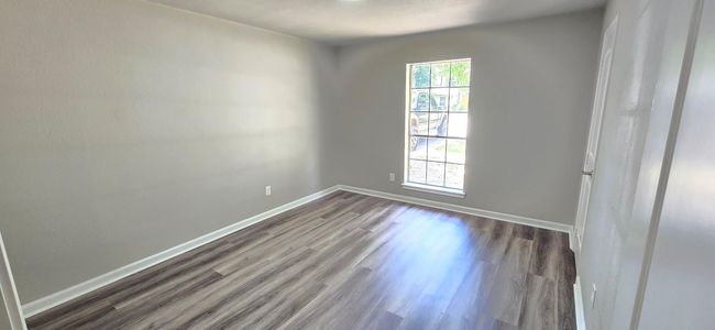 This room features sleek wood look vinyl plank flooring, neutral walls, and a large window that allows natural light to brighten the space. Ideal for a bedroom or office. | Image 16
