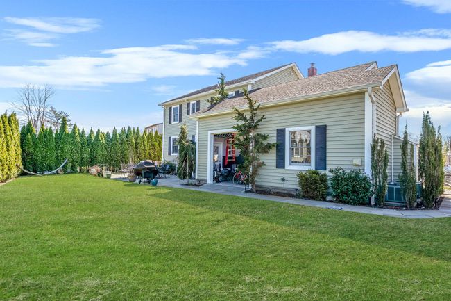 View of front of house featuring a chimney, a garage, a front lawn, and a patio area | Image 31