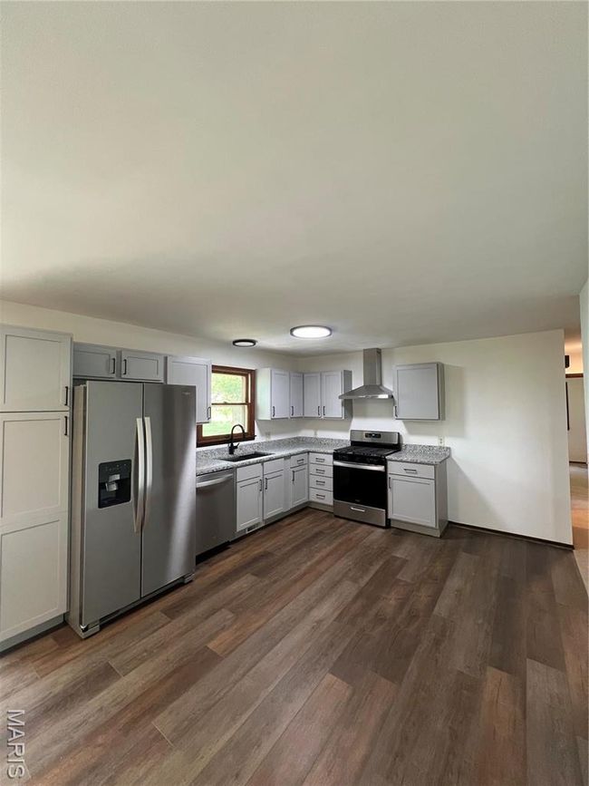 Kitchen featuring fridge, a sink, exhaust hood, dishwashing machine, and stove | Image 18