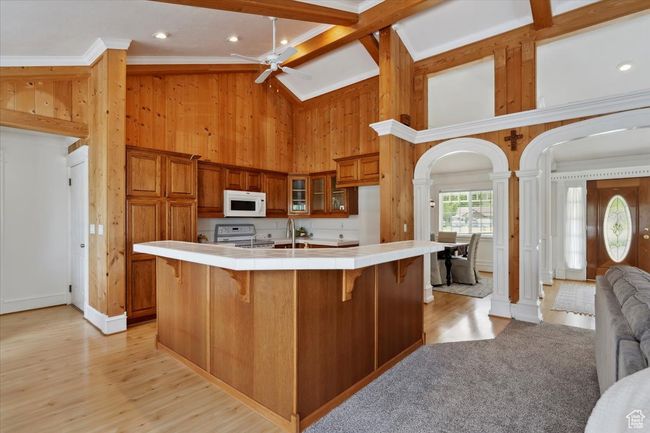 Kitchen with white appliances, tile countertops, ornate columns, crown molding, and ceiling fan | Image 9