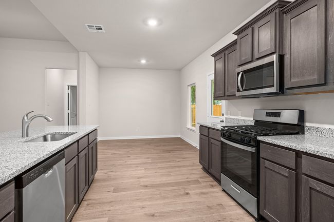 Kitchen with stainless steel appliances, a sink, dark brown cabinets, light wood-style flooring, and baseboards | Image 4