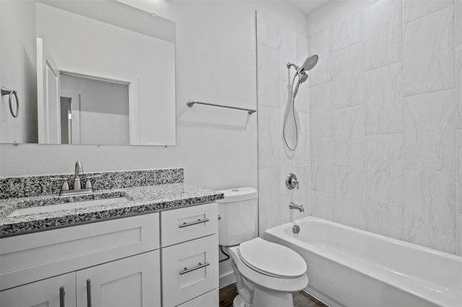 Full bath featuring vanity, washtub / shower combination, and wood finished floors | Image 12