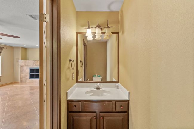Bathroom with vanity, a ceiling fan, tile patterned floors, a fireplace, and a textured wall | Image 17