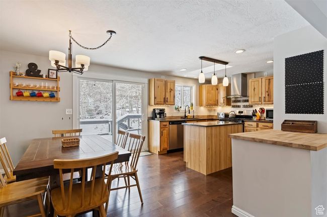 Kitchen with wall chimney range hood, appliances with stainless steel finishes, a kitchen island, dark wood-style flooring, and wood counters | Image 15