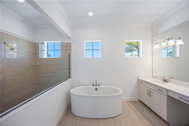 Bathroom with crown molding, a tile shower, vanity, and plenty of natural light | Image 15