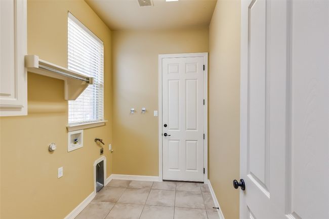 Laundry area with hookup for a gas dryer, hookup for a washing machine, baseboards, laundry area, and light tile patterned floors | Image 34