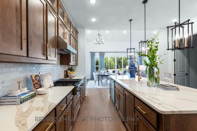 Kitchen with under cabinet range hood, dark wood-style flooring, a chandelier, backsplash, and stainless steel appliances | Image 8