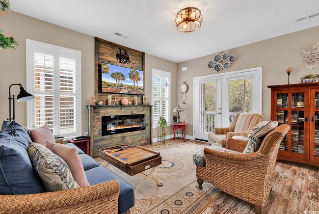 Living area with a stone fireplace, visible vents, wood finished floors, and french doors | Image 5