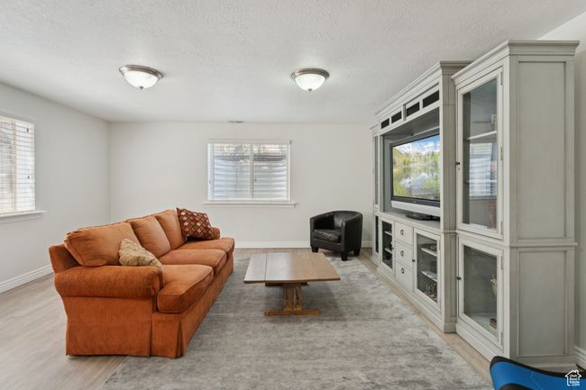 Living area featuring light wood-style flooring, a textured ceiling, and baseboards | Image 26