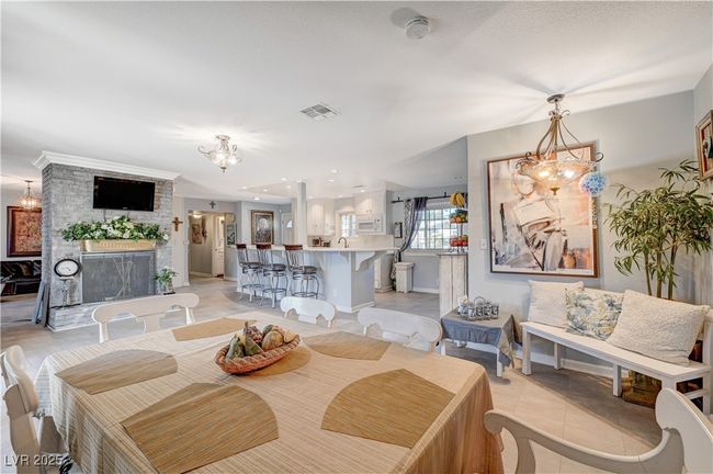 Dining area featuring a chandelier, light tile patterned floors, and a brick fireplace | Image 34
