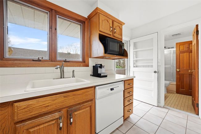 Kitchen with a sink, light tile patterned flooring, visible vents, black microwave, and dishwasher | Image 6