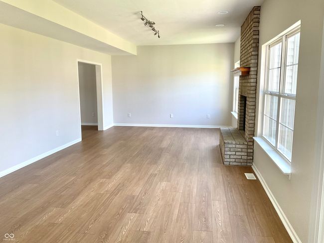 Large open family room and eat-in kitchen area with new flooring and paint. | Image 16