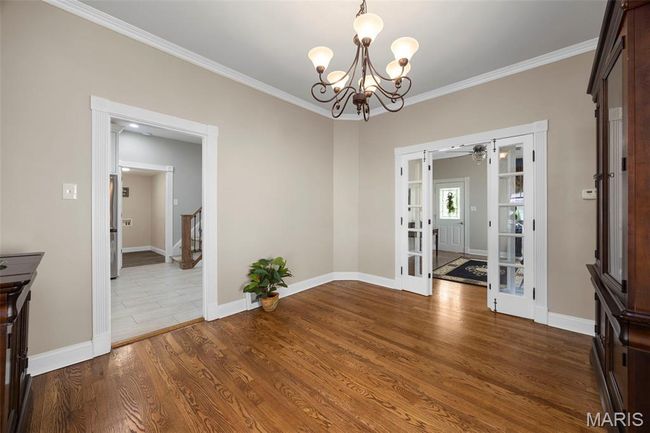 Unfurnished dining area featuring french doors, a chandelier, ornamental molding, and wood finished floors | Image 6