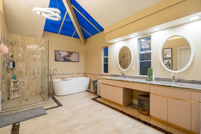 Bathroom with double vanity, a stall shower, a freestanding tub, high vaulted ceiling, and recessed lighting | Image 21