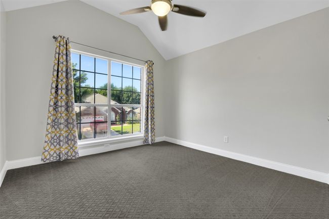 Empty room with lofted ceiling, a ceiling fan, and dark carpet | Image 21