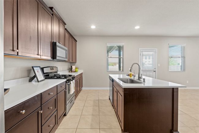 Kitchen with baseboards, a sink, appliances with stainless steel finishes, and light tile patterned flooring | Image 9