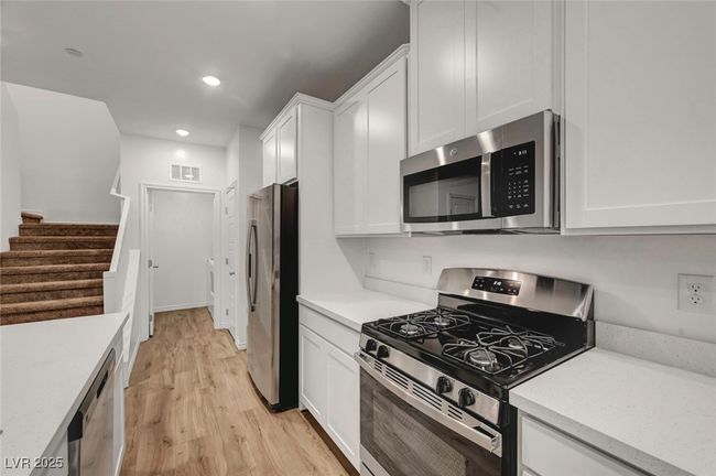 Kitchen featuring recessed lighting, appliances with stainless steel finishes, light wood-type flooring, white cabinetry, and visible vents | Image 18