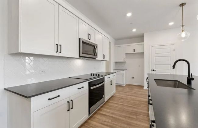 Kitchen with appliances with stainless steel finishes, a sink, dark countertops, tasteful backsplash, and white cabinets | Image 6