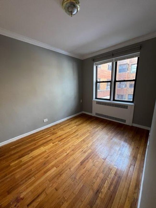 Empty room featuring crown molding, radiator heating unit, wood finished floors, and baseboards | Image 7