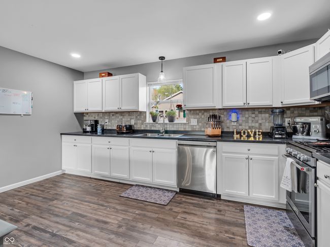 kitchen with recessed lighting, a large sink, tasteful backsplash, dark countertops, and appliances with stainless steel finishes | Image 5