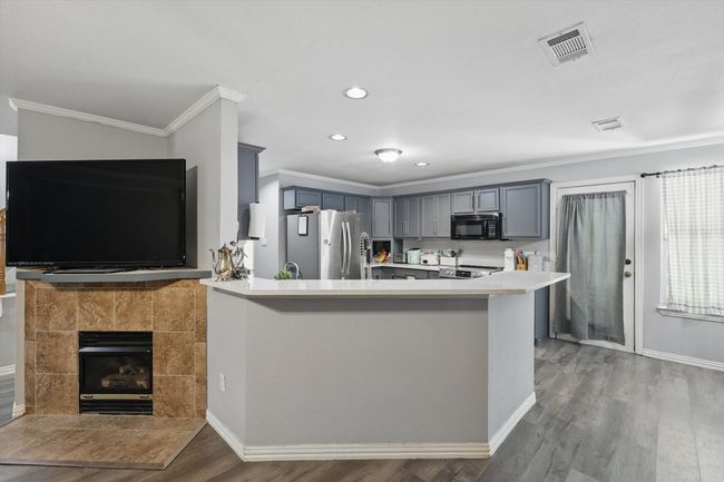 Kitchen with freestanding refrigerator, black microwave, ornamental molding, gray cabinets, and wood finished floors | Image 10